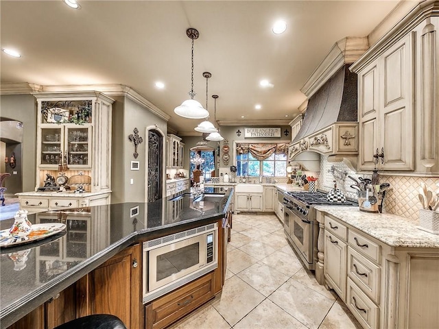 kitchen with decorative backsplash, appliances with stainless steel finishes, crown molding, pendant lighting, and dark stone countertops