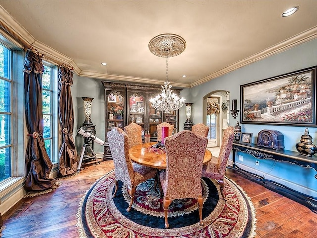 dining area with hardwood / wood-style floors, a notable chandelier, and crown molding