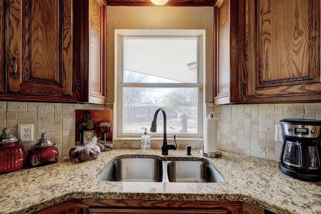 kitchen with decorative backsplash, light stone counters, and sink