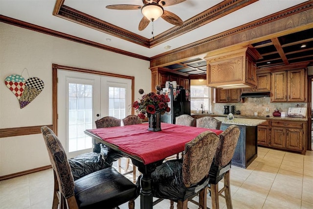 tiled dining space with ceiling fan, french doors, sink, coffered ceiling, and crown molding