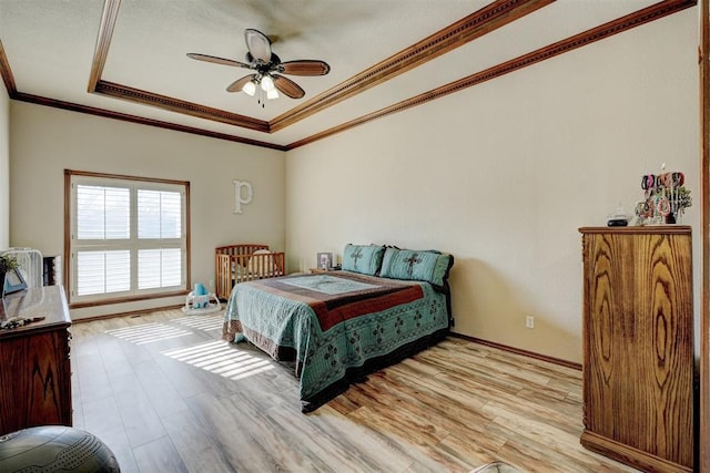 bedroom featuring a raised ceiling, ceiling fan, ornamental molding, and light wood-type flooring