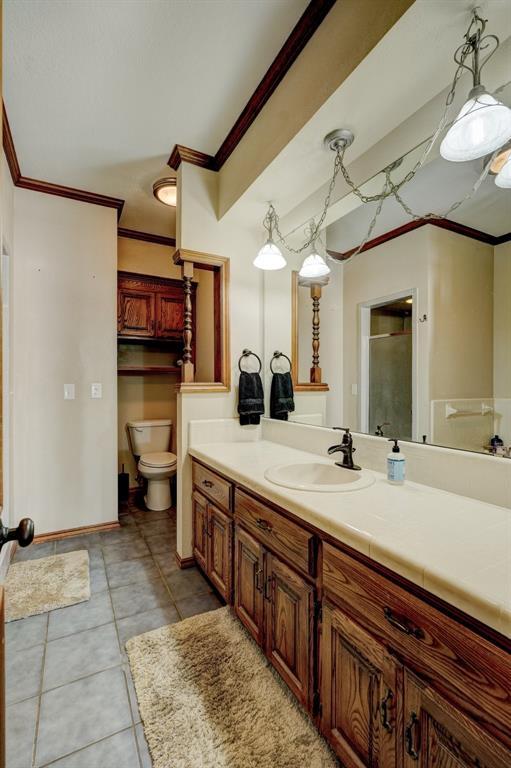 bathroom featuring walk in shower, tile patterned floors, toilet, vanity, and ornamental molding