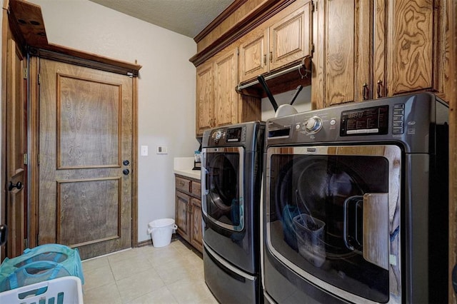 laundry room with cabinets, independent washer and dryer, a textured ceiling, and light tile patterned floors