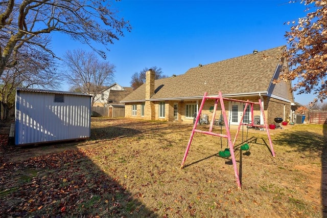 back of property featuring a playground, a shed, and a lawn