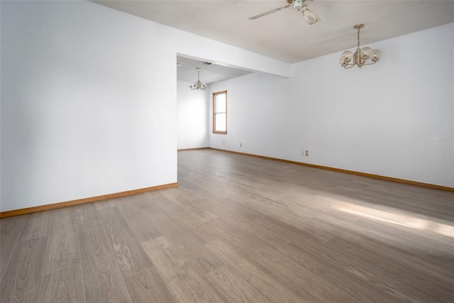 empty room with ceiling fan with notable chandelier and hardwood / wood-style flooring