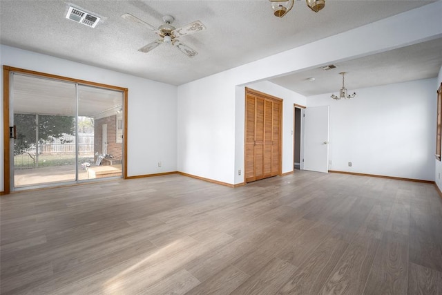 unfurnished room featuring a textured ceiling, ceiling fan with notable chandelier, and hardwood / wood-style flooring