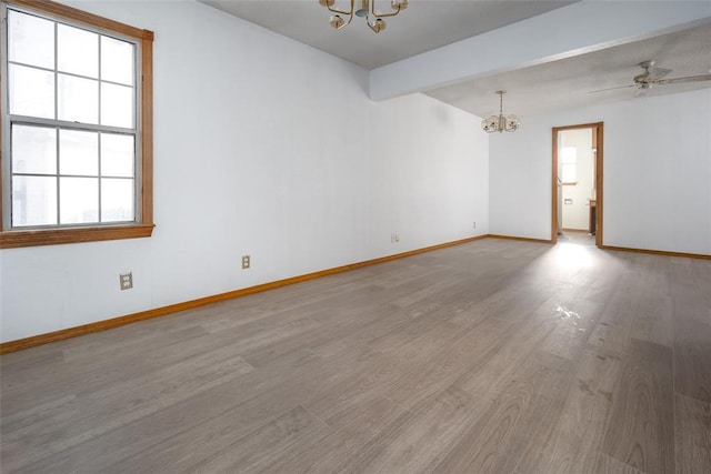 unfurnished room with beamed ceiling, hardwood / wood-style floors, ceiling fan with notable chandelier, and plenty of natural light