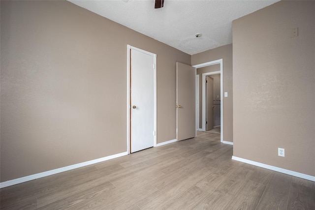 unfurnished bedroom featuring a textured ceiling, light wood-type flooring, and ceiling fan