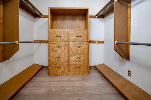 walk in closet with light hardwood / wood-style floors