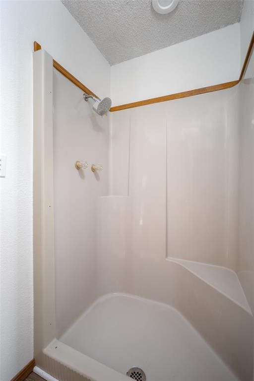 bathroom with a shower and a textured ceiling