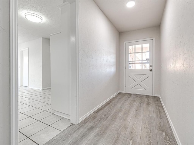 doorway featuring a textured ceiling and light hardwood / wood-style flooring