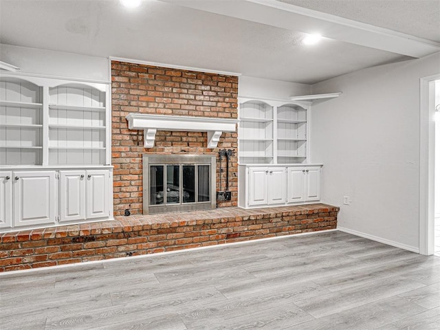 unfurnished living room featuring light wood-type flooring and a brick fireplace