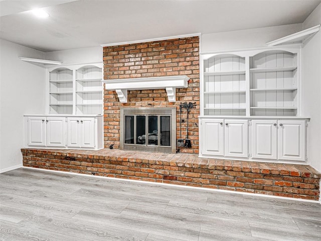 unfurnished living room with light hardwood / wood-style floors and a brick fireplace