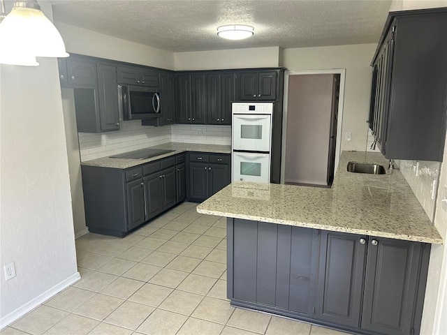 kitchen with white double oven, light stone counters, a textured ceiling, black electric cooktop, and decorative backsplash