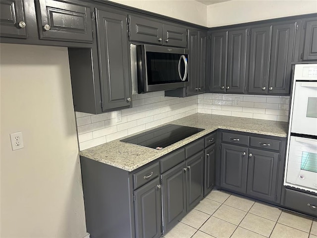 kitchen featuring decorative backsplash, light tile patterned floors, black electric cooktop, and double wall oven