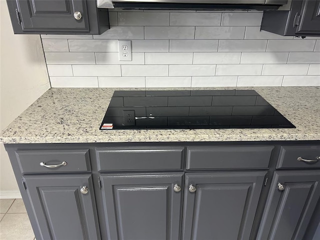 details featuring light stone countertops, black electric stovetop, backsplash, and gray cabinetry