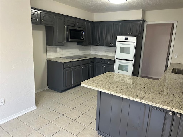 kitchen featuring white double oven, light stone counters, backsplash, kitchen peninsula, and black electric stovetop