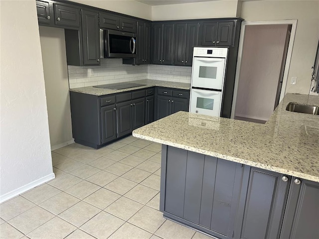 kitchen featuring light stone countertops, kitchen peninsula, white double oven, black electric cooktop, and light tile patterned floors