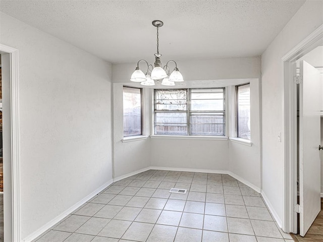 unfurnished dining area featuring light tile patterned flooring, a textured ceiling, and a notable chandelier