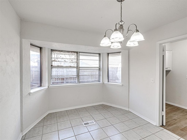 unfurnished dining area featuring light tile patterned floors and a chandelier