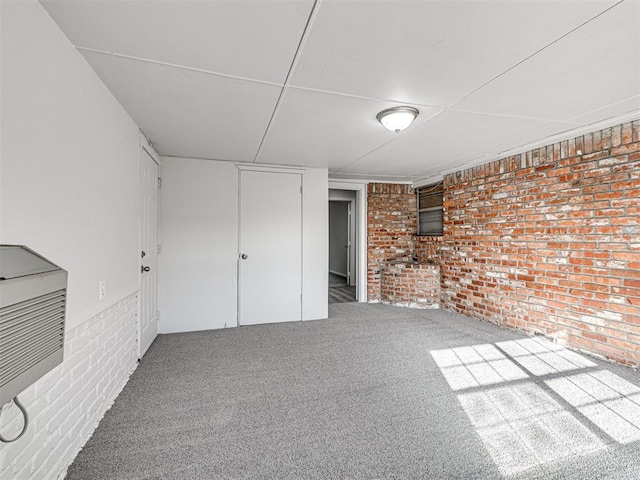 basement with carpet, brick wall, and heating unit