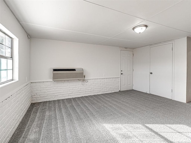 basement with carpet floors, a wall mounted AC, and brick wall