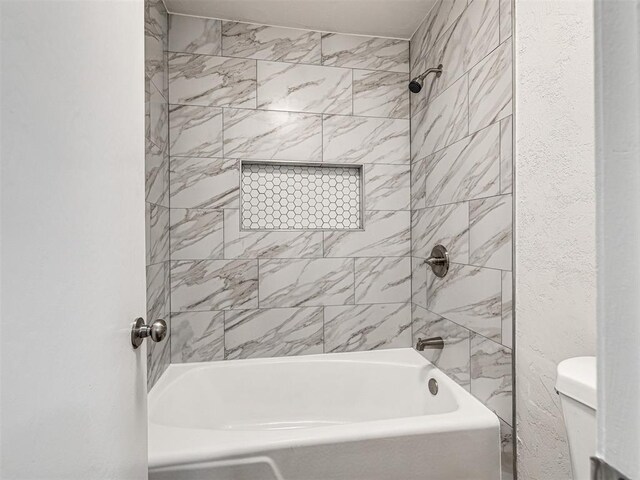 bathroom with tiled shower / bath combo and toilet