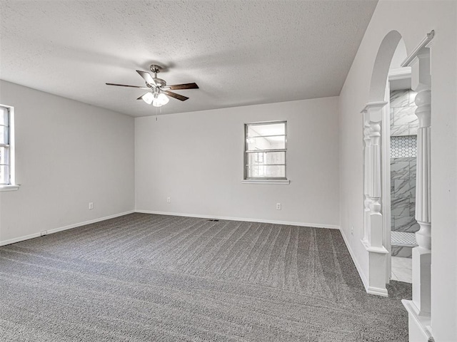 spare room with ceiling fan, a textured ceiling, and dark colored carpet