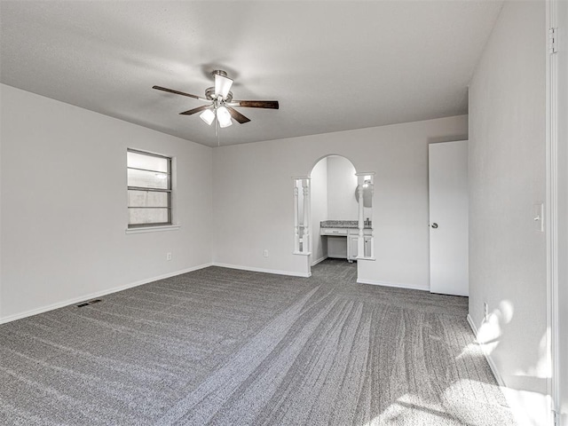 unfurnished living room with dark colored carpet and ceiling fan