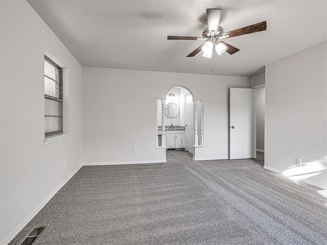 empty room featuring ceiling fan, carpet, and a textured ceiling