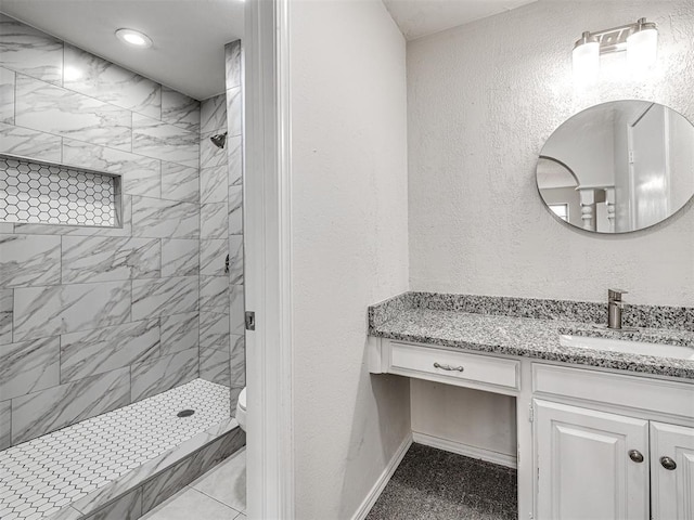 bathroom with toilet, vanity, and tiled shower