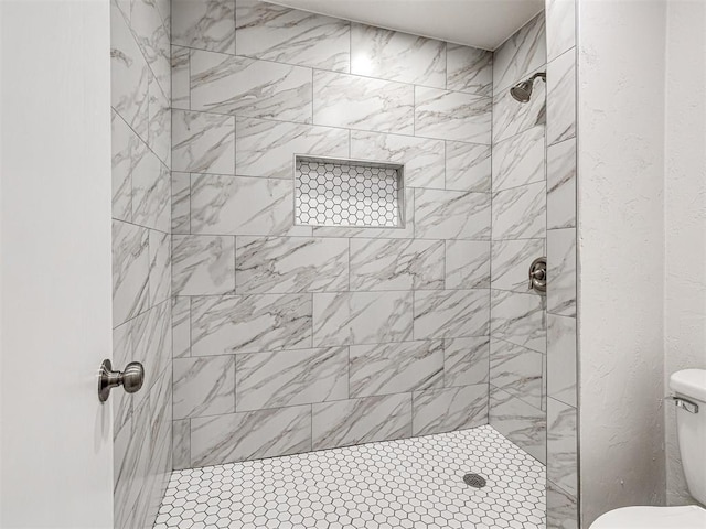 bathroom featuring toilet and tiled shower