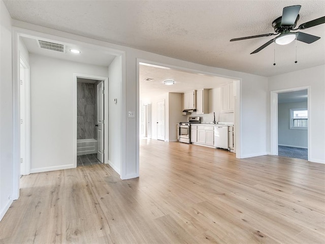 unfurnished living room featuring ceiling fan, sink, light wood-type flooring, and a textured ceiling