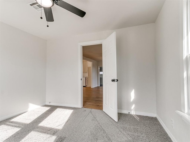 empty room with ceiling fan and light carpet