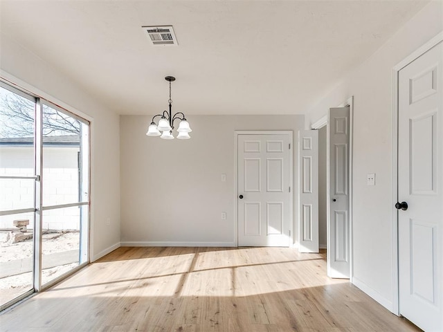 unfurnished dining area featuring light hardwood / wood-style floors and an inviting chandelier