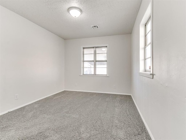 carpeted empty room with a textured ceiling