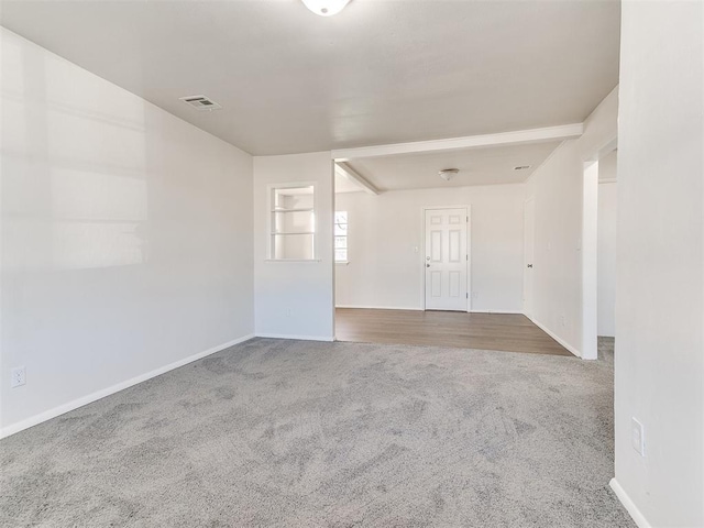 spare room featuring beamed ceiling, carpet floors, and built in features