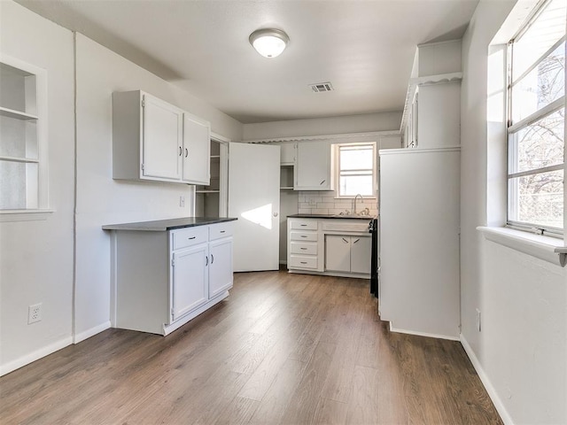 kitchen with backsplash, dark hardwood / wood-style flooring, white cabinetry, and sink