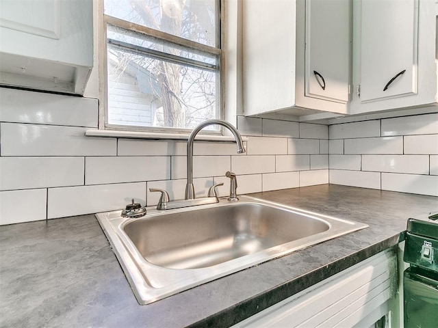 kitchen with backsplash, white cabinetry, and sink