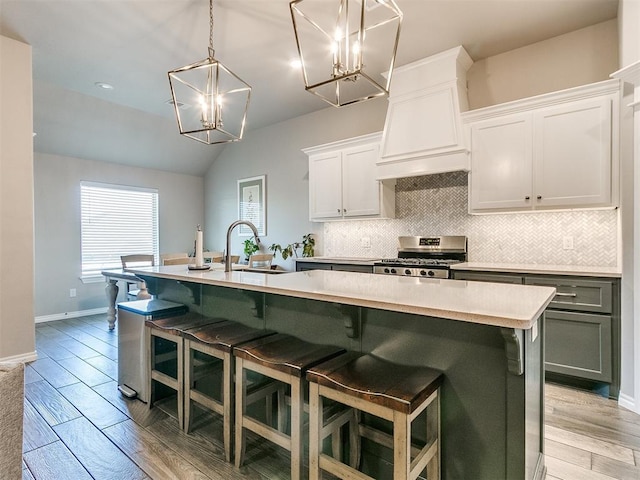 kitchen featuring white cabinets, stainless steel stove, a kitchen island with sink, and light hardwood / wood-style floors