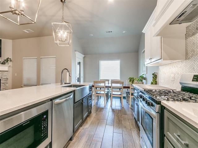 kitchen featuring light wood-type flooring, decorative light fixtures, white cabinetry, stainless steel appliances, and a chandelier