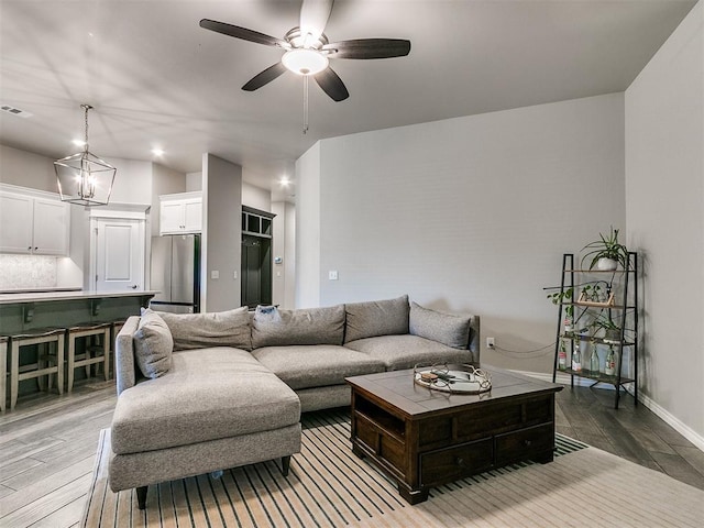 living room with ceiling fan with notable chandelier and wood-type flooring