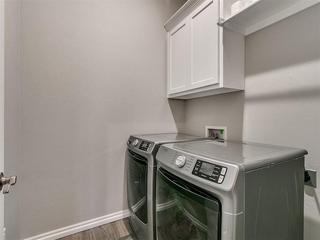 laundry room with washing machine and clothes dryer, dark hardwood / wood-style flooring, and cabinets