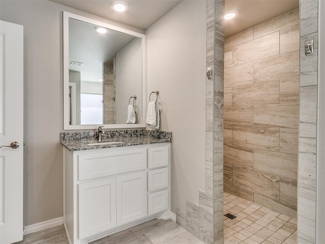 bathroom with hardwood / wood-style flooring, vanity, and tiled shower