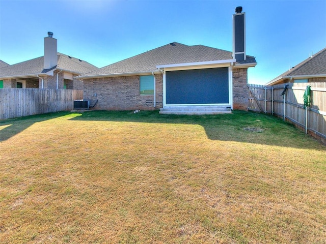 back of house featuring central air condition unit and a lawn