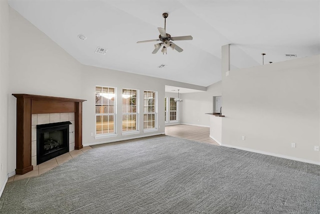 unfurnished living room with a tiled fireplace, ceiling fan, high vaulted ceiling, and light colored carpet