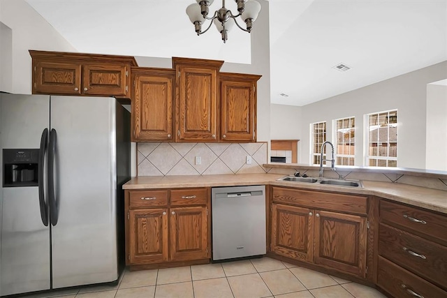 kitchen with sink, stainless steel appliances, backsplash, a chandelier, and light tile patterned flooring