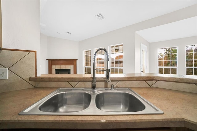 kitchen featuring lofted ceiling, sink, and a tiled fireplace