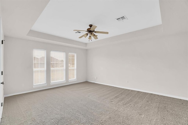 spare room featuring carpet, a raised ceiling, and ceiling fan