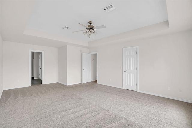 unfurnished room with carpet floors, a tray ceiling, and ceiling fan